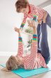 Woman laying on the floor balancing a young boy on her hands and feet wearing the Frugi adults eco-friendly indigo harem trousers