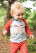 Toddler wearing the grey marl moose organic cotton Frugi top with red pants walking in the woods