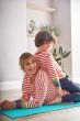 Woman laying on a blue yoga mat with a young boy on her back wearing matching Frugi eco-friendly cordelia box fit tops