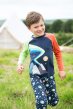 Child wearing the Abisko stars Cosy joggers with an applique raglan sleeve Frugi top, walking in grass with tend in background