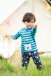 Brown haired toddler wearing Frugi snuggle crawlers with striped top holding hay in front of a tent