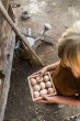 Close up of child holding the Grapat eco-friendly square wooden toy box, filled with large hens eggs