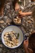 Close up of children playing with the Grapat eco-friendly natural wood mandala pieces in a white bowl on some small pebbles