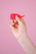 Hey Girls Large red Silicone Menstrual Cup folded in someone's hand on a pink background