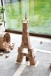 Just Blocks wooden waldorf toy shapes stacked in the shape of an Eiffel Tower on a grey carpet