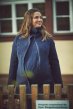 Mamalila Eco Wool Oslo Babywearing Coat in Navy. A navy blue organic boiled wool winter babywearing coat. Front lifestyle view, collar up, with pregnancy insert on front. House background.  