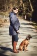 Mamalila Dublin Babywearing Rain Coat in Navy. Side lifestyle view with maternity insert. Woodland background walking a dog