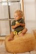 Child sat on a bean bag holding the oli and carol eco-friendly soft fruit and nut rubber pistachio toy