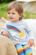 Blonde toddler wearing rainbow applique oscar outfit with grey marl top and rainbow stripe pants sitting down