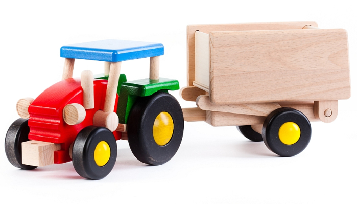 The Bajo wooden tractor and Trailer toy, made from solid hardwood with a red, green and blue painted finish and natural wood trailer. 