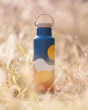 The Klean Kanteen 20oz / 592ml Insulated Classic Loop Cap Bottle - Mountains. An artistic Mountain print with soft curved mountain in burnt orange, yellow and white, with a large yellow sun on a blue bottle. With a beige loop cap on a grassy background