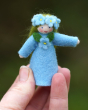 Close up of a hand holding an Ambrosius forget me not fairy figure in front of a green background