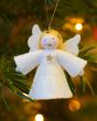 Ambrosius eco-friendly felt angel figure hanging from a Christmas tree in front of some blurred lights