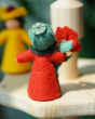 A view of the back of an Ambrosius poppy boy felted figured placed on a Grimm's wooden display stand 