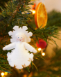 Ambrosius handmade felt snow crystal figure hanging in a Christmas tree in front of a slice of dried orange
