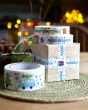 Babipur Christmas design recyclable eco paper tapes alongside a package wrapped with brown paper and using the Welsh Nadolig Llawen design tape 