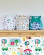 Tots Bots, Baba and Boo and Close Pop-In eco friendly reusable nappies on a wooden shelf above a Babipur world wallpaper print
