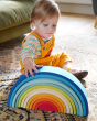 A child happily playing with a Babipur Gwawr Rainbow, wearing the Frugi x Babipur yellow natural organic cotton cord dungarees 