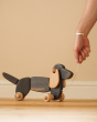 Close up of hand pulling the string on the Bajo dark oak dachshund pull along toy dog
