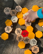 Close up of a hand playing with the Bajo plastic-free hive block toys on a wooden log