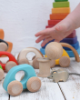 A small world play set up with a Grimm's Wankle in the background. A child's can be seen dropping a Grapat natural ball. The light blue coloured Bajo mini car can be seen at the front.