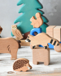 A racoon figure from the Bajo forest animals set can be seen stood on one of the wooden blocks from the Bajo truck. The hedgehog figure stands at the front and other animals can also be seen in the background 