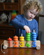 A child playing with the Bajo 1-5 Pull Along Number Stacker placed on a wooden table. 