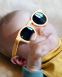 Close up of toddler laying down wearing the Bird eco-friendly flexible sunglasses