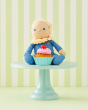 Bonnie Buttercream is sat on a cake stand behind a delicious cupcake, on a green and white stripe background