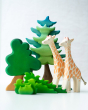 2 Ostheimer giraffe figures on a white background next to a Bumbu wooden Spruce tree and shrub bush toys