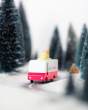 Close up of the Candylab wooden ice cream van toy on a black toy road surrounded by small trees and snow