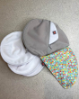Close maternity breast feeding pads on a grey floor next to the Close pastel print pad pouch