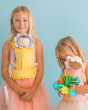 Two children wearing petal carriers whilst carrying sleepy Dinkum dolls, on a blue backgorund