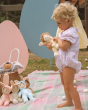 A child happily playing with the Olli Ella Dinky Dinkum Doll Fluffles collection, holding Babbit Bunny