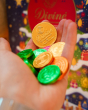 Close up of a hand holding the fairtrade Divine dark chocolate coins in front of a Divine christmas calendar