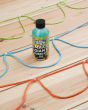 Close up of the Dr Zigs 10x concentrated bubble mixture on a wooden floor next to some coloured rope bubble blowers