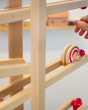 Close up of a hand rolling the Fagus wooden spiral disc toy down a Fagus wooden marble run set