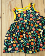 Close up of the DUNS Sweden organic cotton black citrus sleeveless gather skirt dress on a wooden floor