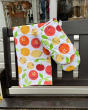 DUNS eco-friendly organic cotton oven glove and tea towel in the citrus print hanging over the end of a black bench 