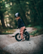 Young girl sat on the Early rider charger balance bike, on a gravel trail in the woods