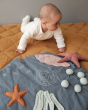 Baby crawling over a quilted duvet next to the Fabelab soft organic cotton underwater activity blanket