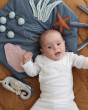 Baby laying on the Fabelab organic cotton activity blanket in the underwater design