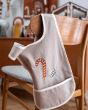 Fabelab kids organic cotton cross back bib with an embroidered candy cane, hanging from a wooden chair