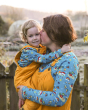 Woman carrying and kissing a little boy wearing the Babipur x Frugi organic cotton top 