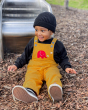 A child happily playing outside at a park, whilst wearing the Frugi x Babipur yellow organic cotton cord dungarees with red elephant 