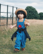 A child happily playing outside in a field wearing the Blue Frugi x Babipur natural organic cotton cord dungarees with red elephant