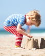 Child bent over playing with a sand castle wearing the Frugi striped orwin outfit
