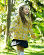 Young girl stood in the woods wearing the Frugi eco-friendly giraffe print puddle buster jacket