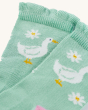 A closer view of the mint green frilled socks, with a white duck and white flower print, on a cream background