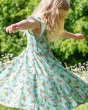 A child twirling around in the sun whilst wearing the Frugi GOTS Organic Cotton Morwenna Skater Dress - Riverine Rabbits. The perfect short sleeve dress for Easter in light green, with a beautiful rabbit, flower and insect print. The print of the dress sh